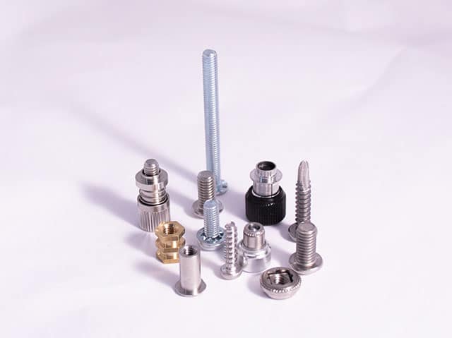 Assorted metal fasteners including bolts, nuts, and screws on a white background for industrial supply.