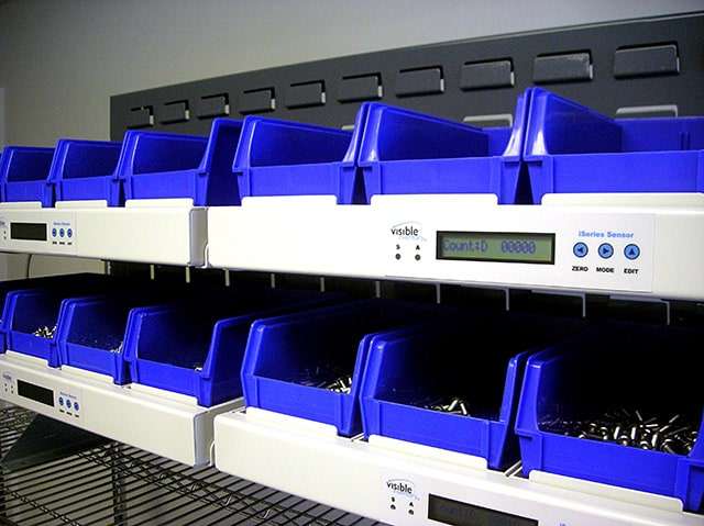 Automated inventory management system with blue bins and digital labeling for efficient parts organization.